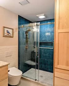 Blue subway-tile shower with frameless glass.