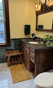 Warm traditional bath, green wainscot, dark-stained oak vanity.